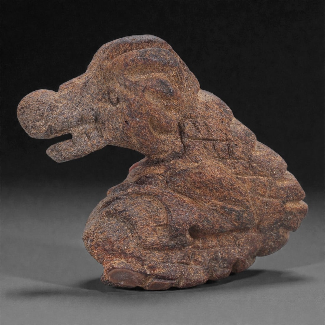 Ancient Fossil Bone Stone Zoomorphic Effigy - Crouching Animal Form, 90E: This expressive zoomorphic effigy is carved from dense fossilized bone stone and depicts a crouching or seated animal rendered in a compact, powerfully modeled form. The figure is shown with the body