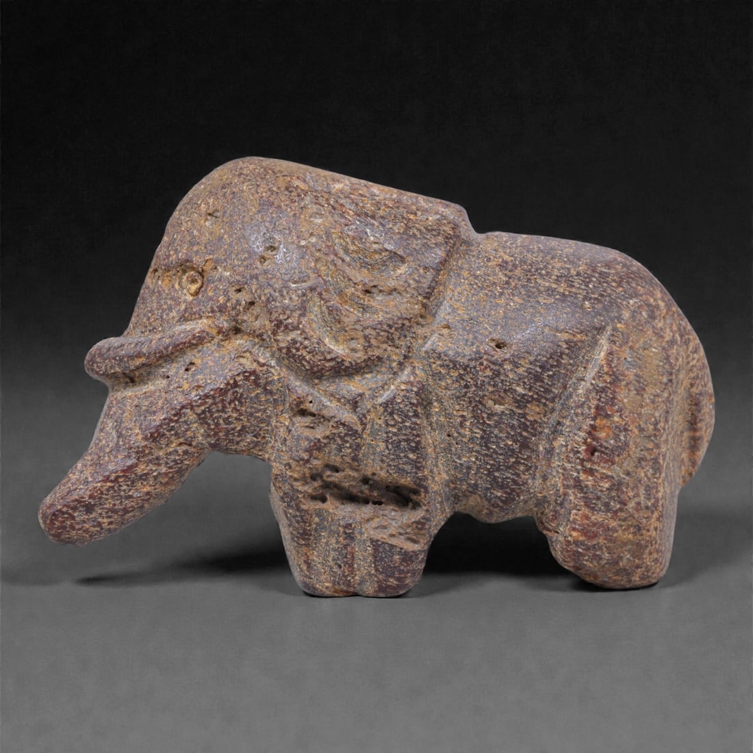 Ancient Fossil Bone Stone Elephant Effigy - Zoomorphic Carving, 10F: This compact zoomorphic effigy is carved from dense fossilized bone stone and represents an elephant rendered in a simplified, archaic style. The form is immediately recognizable through the elongated