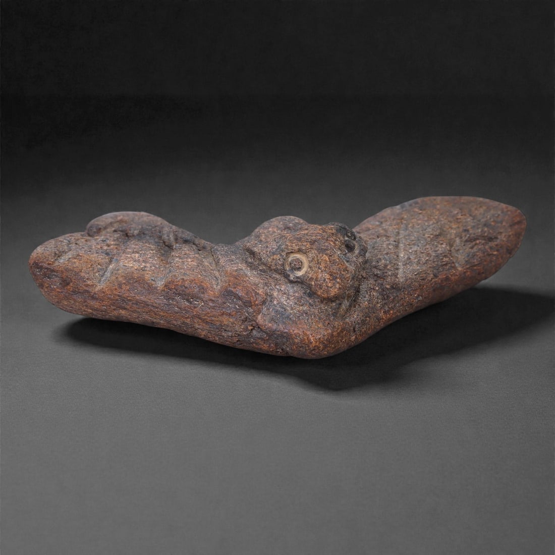 Ancient Fossil Bone Stone Bird Effigy - Zoomorphic Avian Sculpture, 7E: This elongated zoomorphic effigy is carved from dense fossilized bone stone and represents a bird rendered in a highly stylized, archaic manner. The form is horizontal and streamlined, emphasizing the