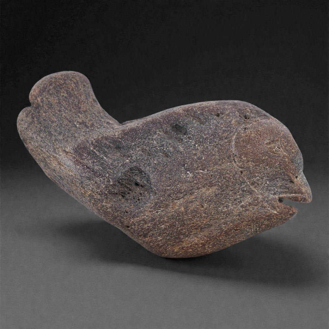 Ancient Fossil Bone Stone Zoomorphic Effigy - Stylized Bird Form, 95E: This refined zoomorphic effigy represents a bird rendered in a compact, elongated form and carved from dense fossilized bone stone. The sculpture emphasizes flow and mass rather than anatomical detail