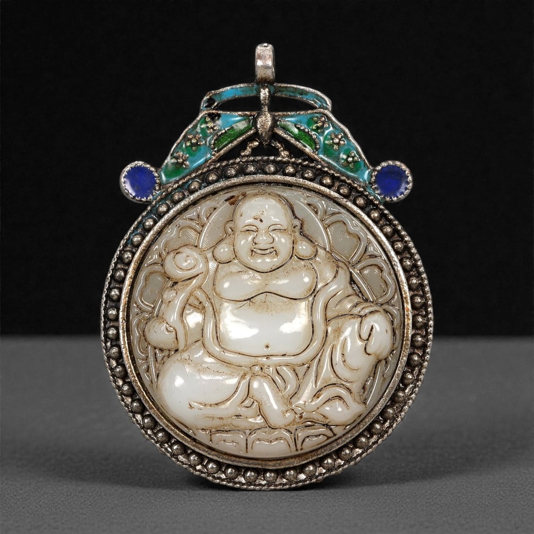 Chinese Jade Laughing Buddha Pendant - Carved Relief Medallion 6.2cm, 1ZE: Carved from pale jade with soft translucency, this circular pendant depicts the Laughing Buddha (Budai) rendered in rounded relief, seated with exposed belly and a broadly smiling expression. The figu