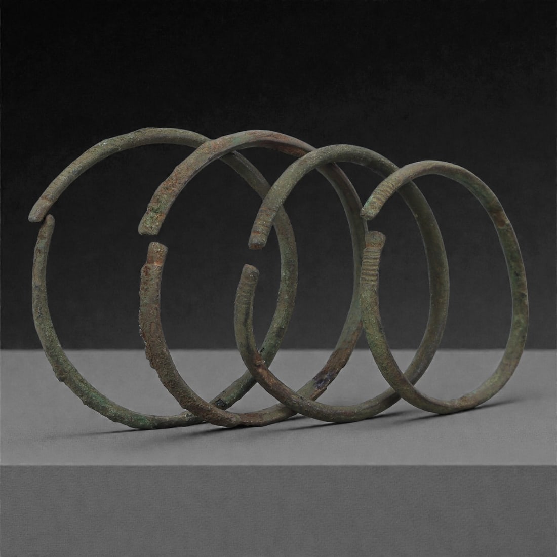 A Group of Roman Bronze Bracelets, 1st-3rd Century CE, 64H: Cast in bronze and formed as slender open circular bands, the bracelets display narrow rounded profiles with slight irregularities resulting from ancient manufacture and later burial conditions. Sever