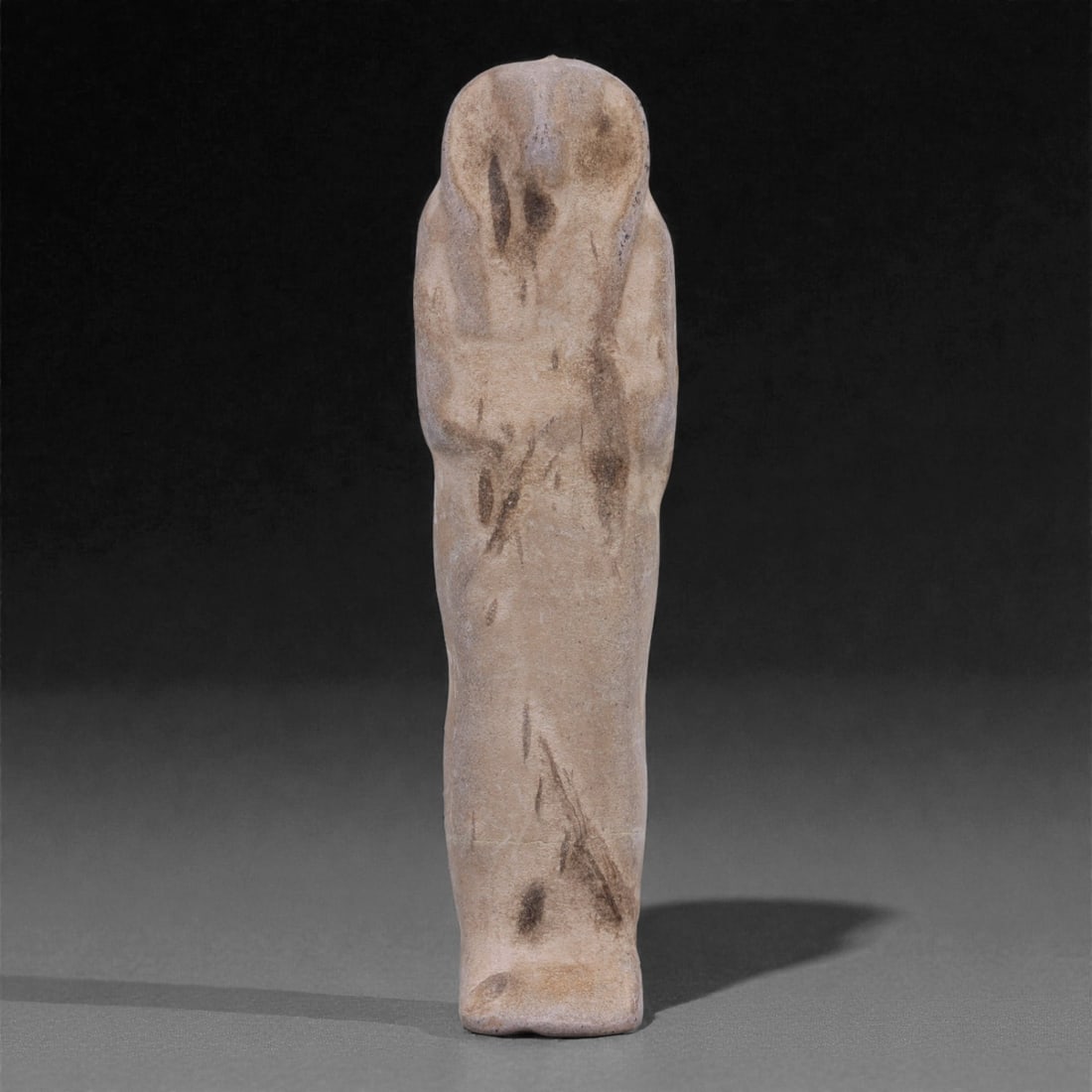 Egyptian Revival Stone Idol - Mummiform Figure, 95G: Carved from light brown stone with a fine, compact texture, this slender mummiform figure presents a simplified Egyptian-inspired form with a rounded head, subtly indicated shoulders, and arms suggest