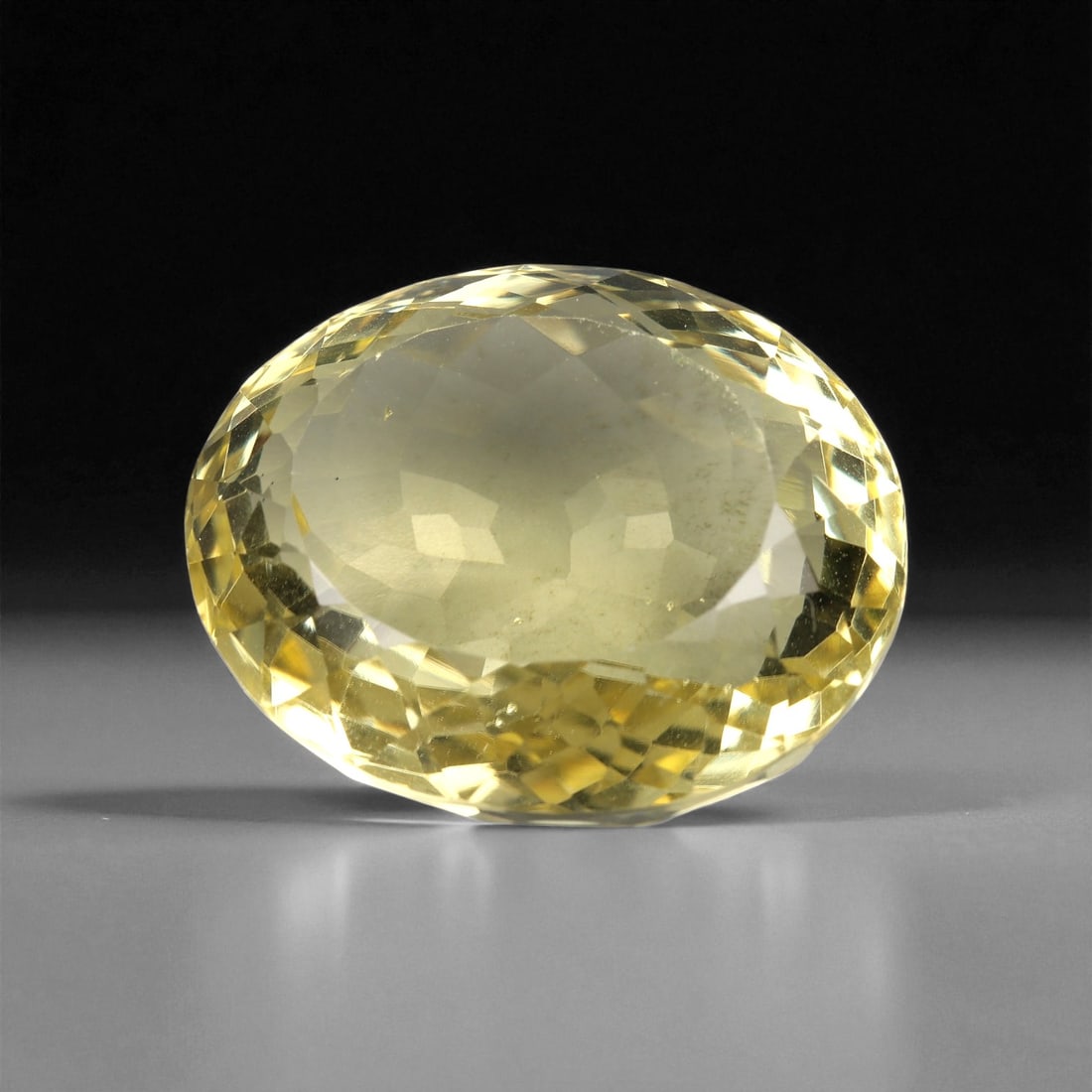 51.44 Carats Lemon Yellow Quartz Oval - Natural Brazilian Faceted Gem, 58XB: This vibrant lemon quartz dazzles with a fresh, zesty yellow hue and exceptional brilliance. Expertly cut into a large oval with checkerboard facets across the crown, it captures and reflects light wi