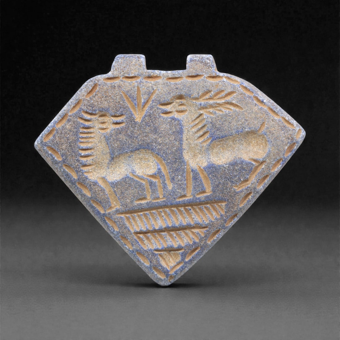 A Sasanian Lapis Lazuli Amulet, 3rd-7th Century CE, 5.5cm, 26Q: Carved from deep blue lapis lazuli with visible lighter inclusions and natural granular texture, the object is finished with a flat reverse and a front surface worked in low relief. The carving is exe