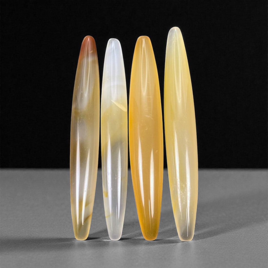 Tibetan Carnelian Ritual Beads, 19th-20th Century CE, 6.3-6.7cm, 5L: Carved from translucent orange carnelian with natural internal banding, the group comprises elongated, double-conical elements with smoothly polished surfaces. Each bead is unperforated, indicating a 
