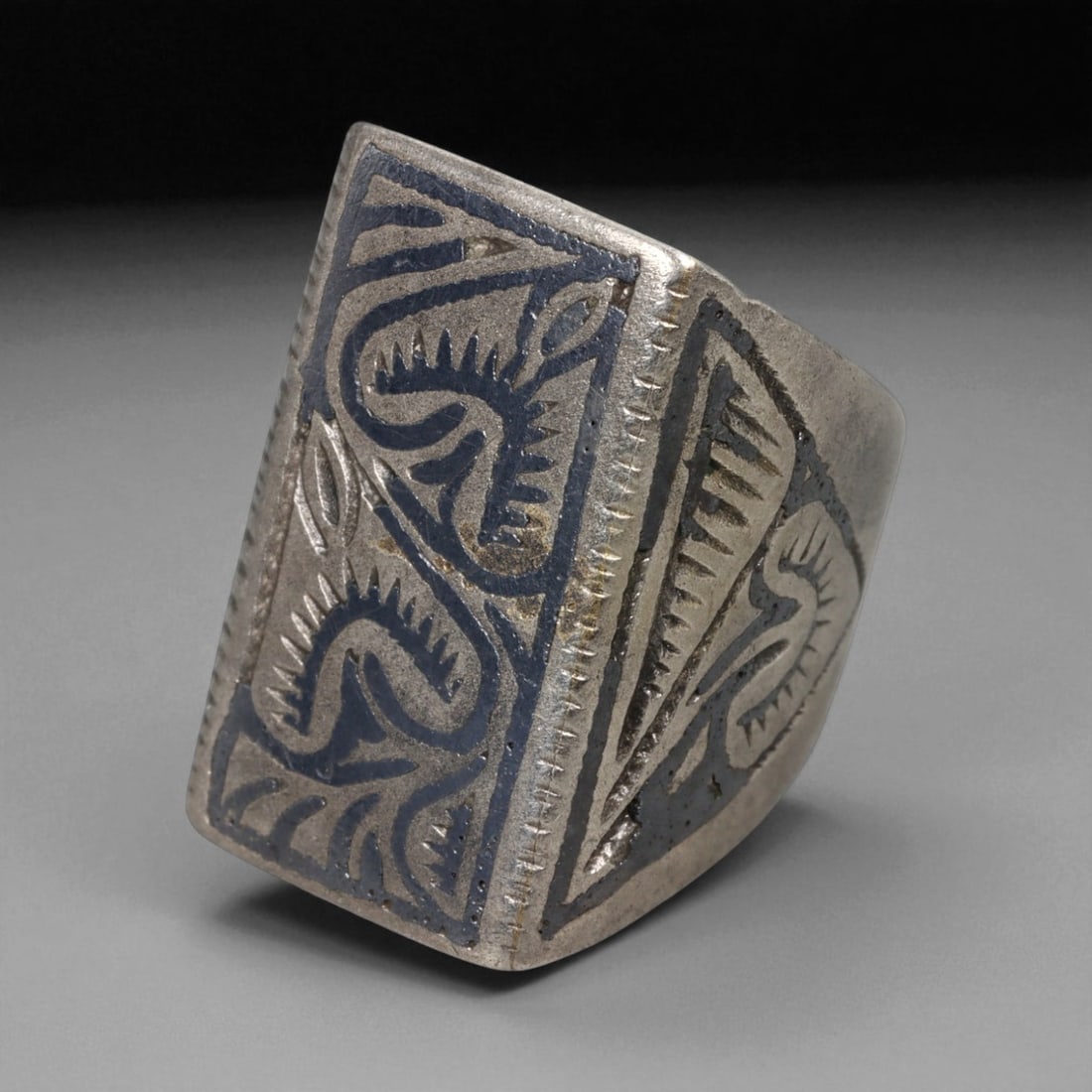Antique Central Asian Engraved Geometric Silver Ring, c. 19th-20th Century 6g, 82BD: This antique silver ring, dating from the 19th-20th century, features a bold rectangular bezel decorated with deeply engraved motifs in darkened relief. The abstract, curling forms resemble stylized v