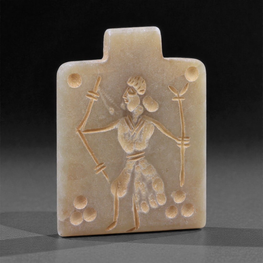 An Eastern Iranian Serpentine Amulet, Islamic Period, 9th-10th Century CE, 4.7cm, 2K: Carved from pale green serpentine with a smooth, slightly translucent surface, the object is worked in low relief on one face, with the reverse left plain and undecorated. The carved elements are defi