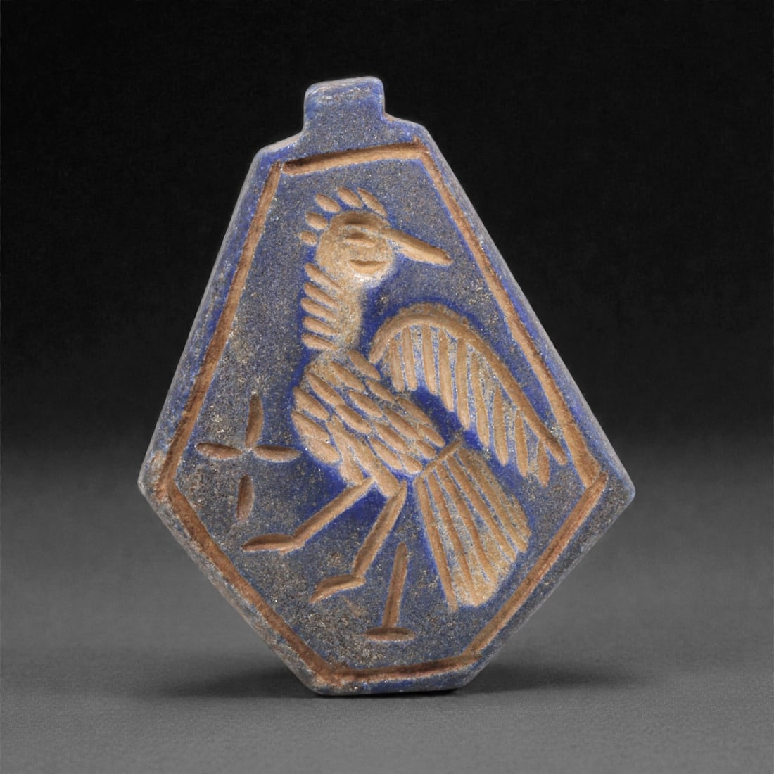 A Sasanian Lapis Lazuli Amulet, 3rd-7th Century CE, 4.1cm, 21Q: Carved from deep blue lapis lazuli with visible lighter inclusions and natural granular texture, the object is finished with a flat reverse and a front surface worked in low relief. The carving is exe