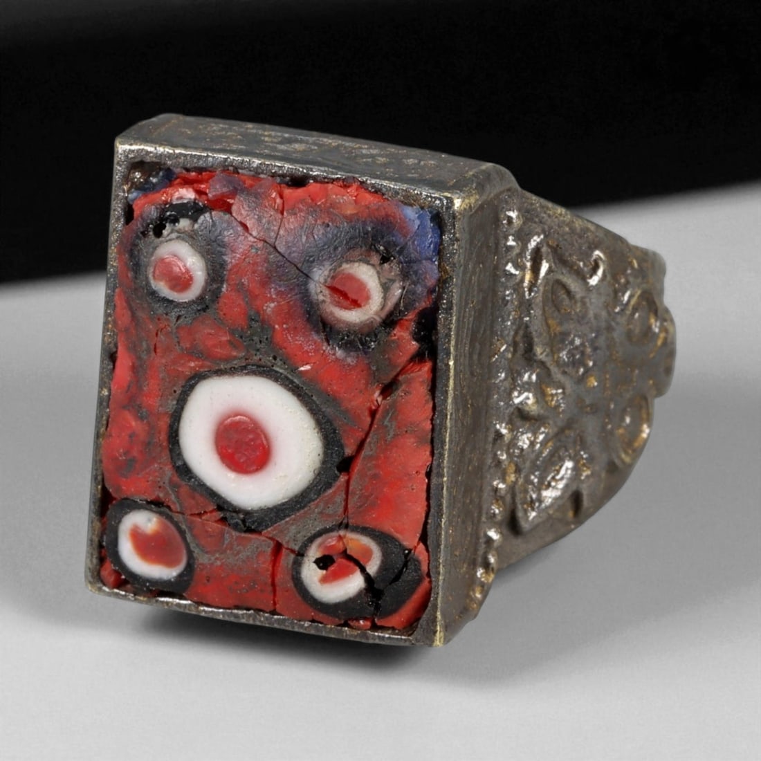 Antique Persian Mosaic Glass Evil Eye Silver Ring, c. 19th-20th Century 15g, 72N: This bold antique silver ring, dating from the 19th-20th century, features a rectangular bezel set with a striking mosaic glass inlay. The design, dominated by concentric red and white circles against