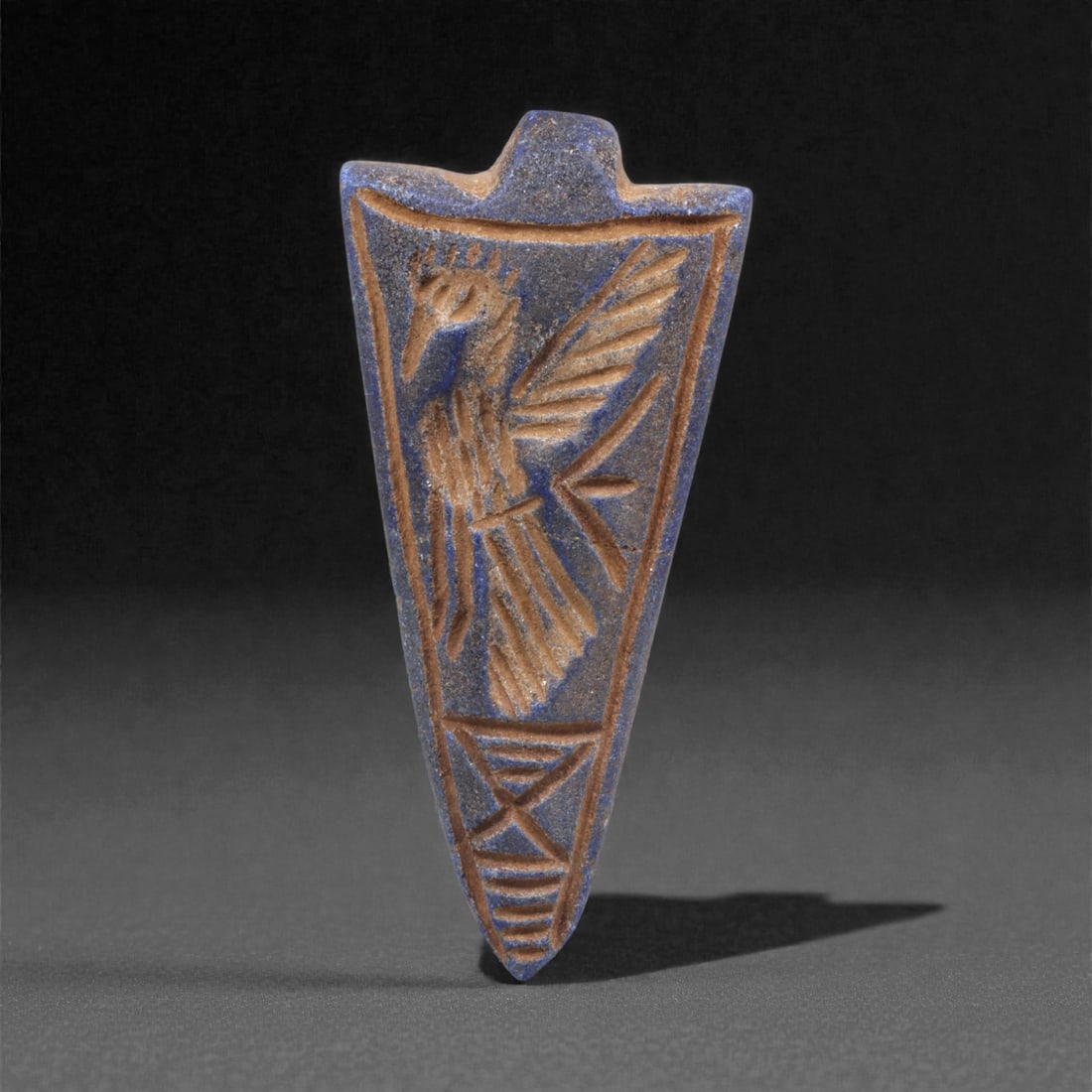 A Sasanian Lapis Lazuli Amulet, 3rd-7th Century CE, 4.6cm, 52Q: Carved from deep blue lapis lazuli with visible lighter inclusions and natural granular texture, the object is finished with a flat reverse and a front surface worked in low relief. The carving is exe