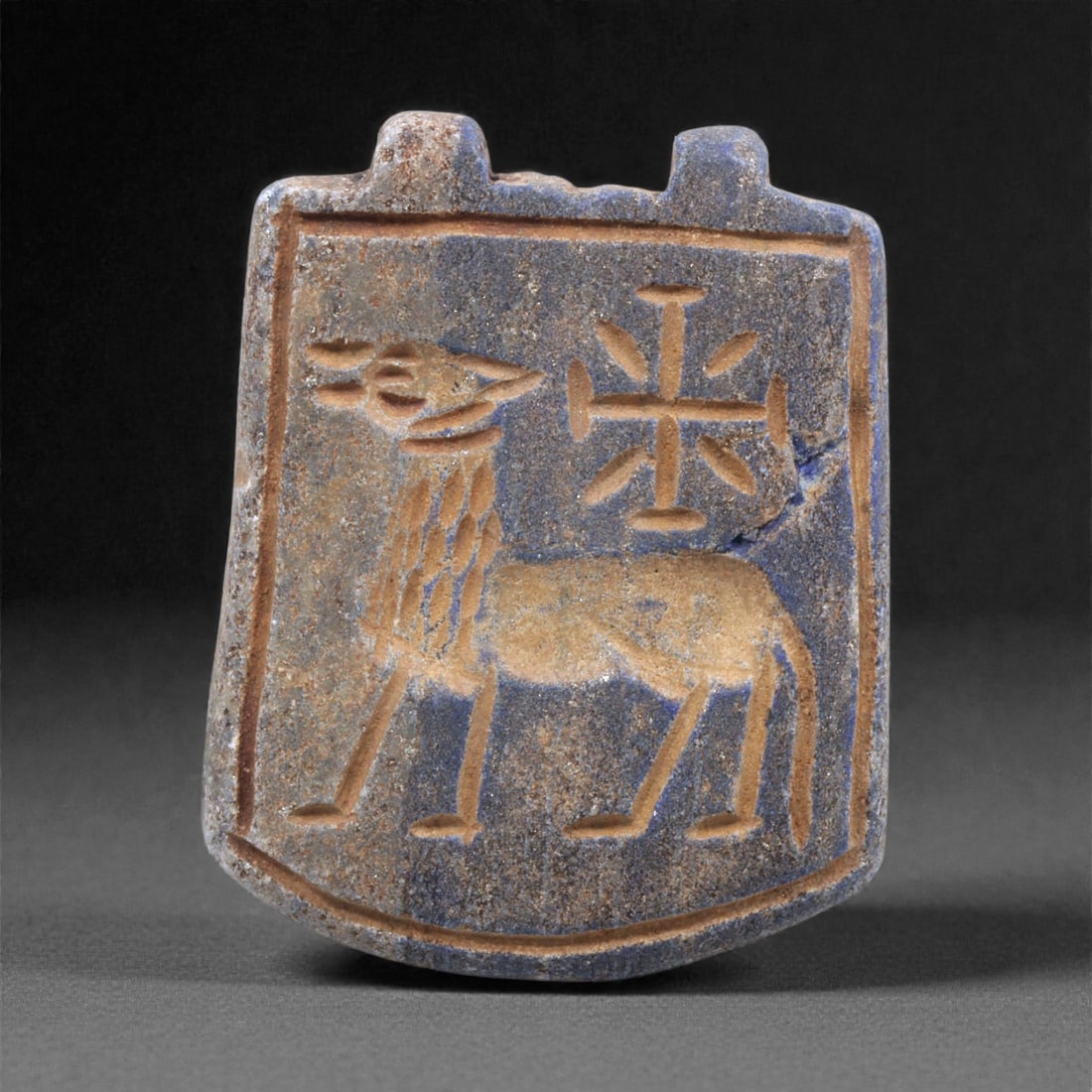 A Sasanian Lapis Lazuli Amulet, 3rd-7th Century CE, 4cm, 5Q: Carved from deep blue lapis lazuli with visible lighter inclusions and natural granular texture, the object is finished with a flat reverse and a front surface worked in low relief. The carving is exe