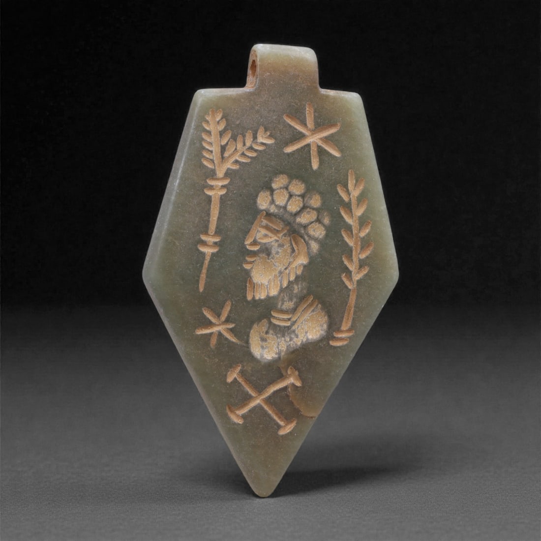 An Eastern Iranian Serpentine Amulet, Islamic Period, 9th-10th Century CE, 5.5cm, 83N: Carved from pale green serpentine with a smooth, slightly translucent surface, the object is worked in low relief on one face, with the reverse left plain and undecorated. The carved elements are defi