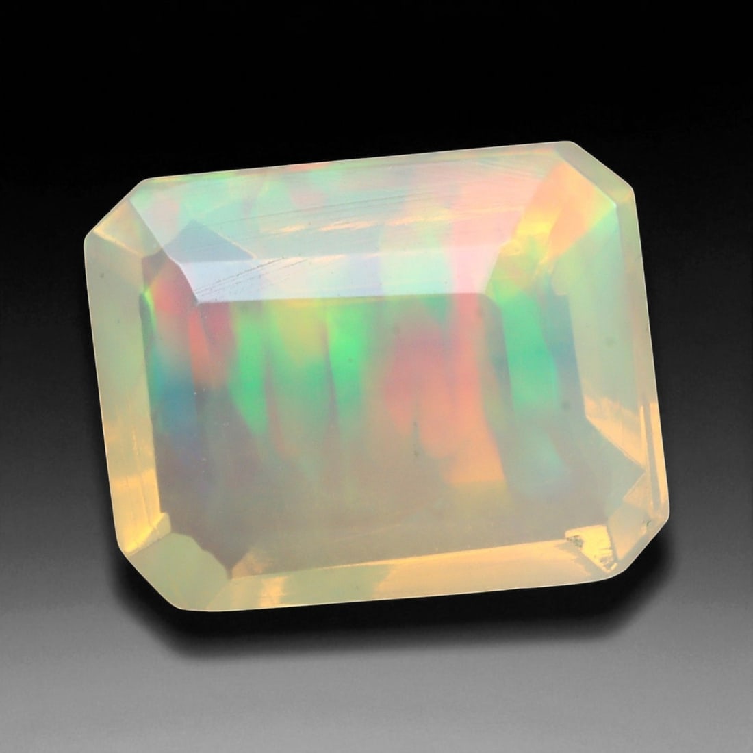 1.88 Carats Faceted Welo Opal - Natural Ethiopian Stone, 4XB: This graceful 10x7.7x4.5 mm Ethiopian opal radiates a soft yet vibrant play-of-color, with hues of green, orange, and rose blending harmoniously beneath its faceted surface. The gem displays a fluid m