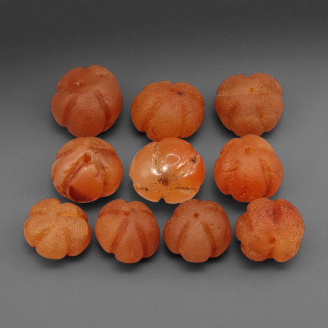 Ancient Medieval Indian Melon-Cut Carnelian Bead Set, c. 10th-13th Century, 1-1.3cm, 82EA: This collection of ten hand-carved melon-form carnelian beads reflects the exquisite lapidary craftsmanship of medieval India between the 10th and 13th centuries CE, likely during the later Chola or e