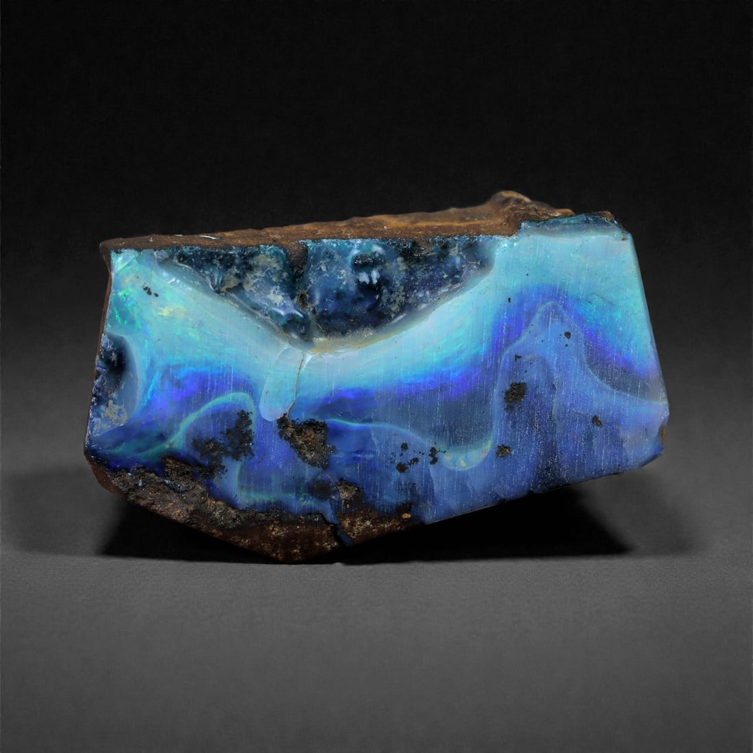 27.33 Carats Ocean Blue Boulder Opal Rough - Natural Winton, Australia, 62XC: This 23 x 14 mm boulder opal rough glows with luminous striations of ocean blue, violet, and turquoise-flowing across the surface like currents beneath a crystal sea. Rich play-of-color appears in ban