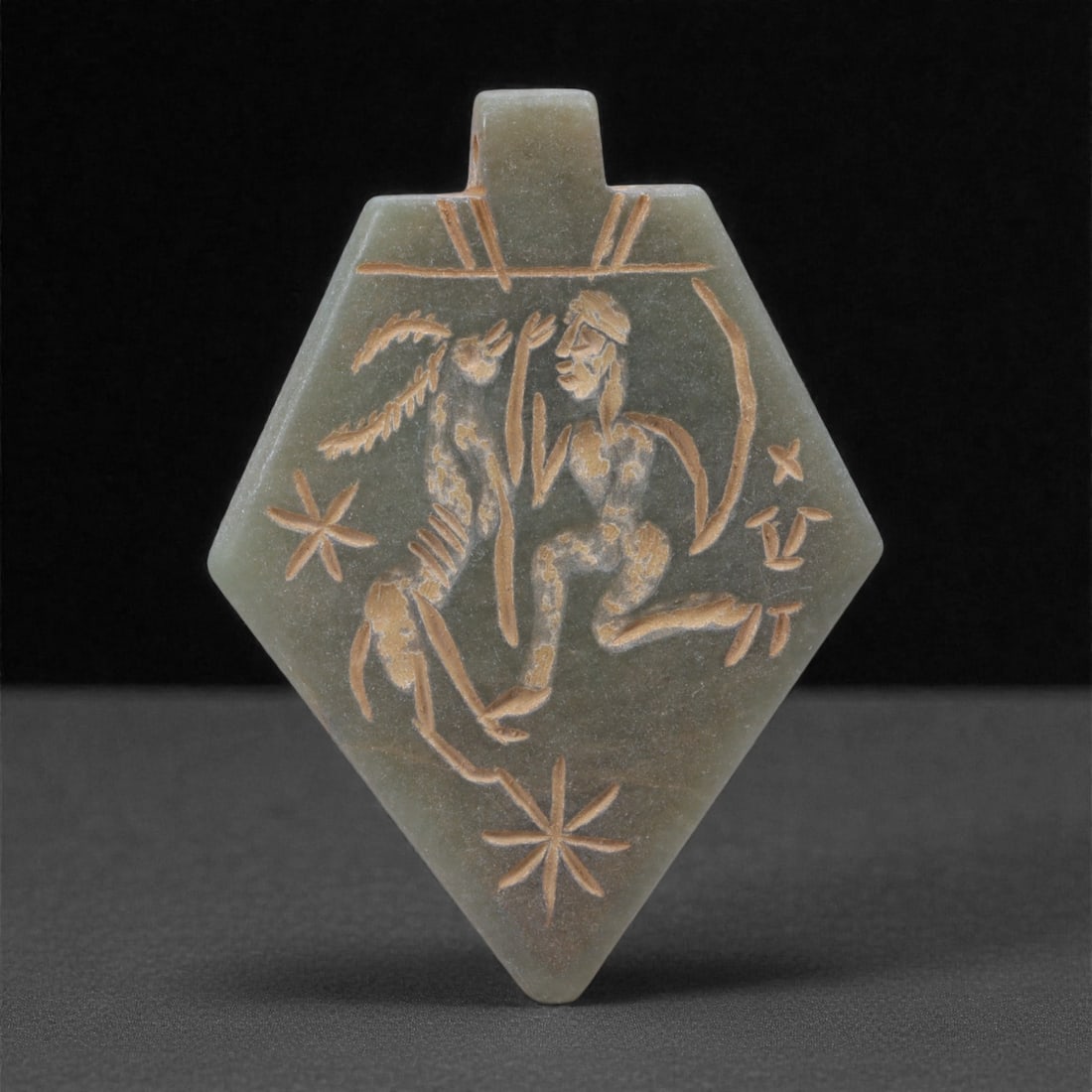 An Eastern Iranian Serpentine Amulet, Islamic Period, 9th-10th Century CE, 5.4cm, 85N: Carved from pale green serpentine with a smooth, slightly translucent surface, the object is worked in low relief on one face, with the reverse left plain and undecorated. The carved elements are defi