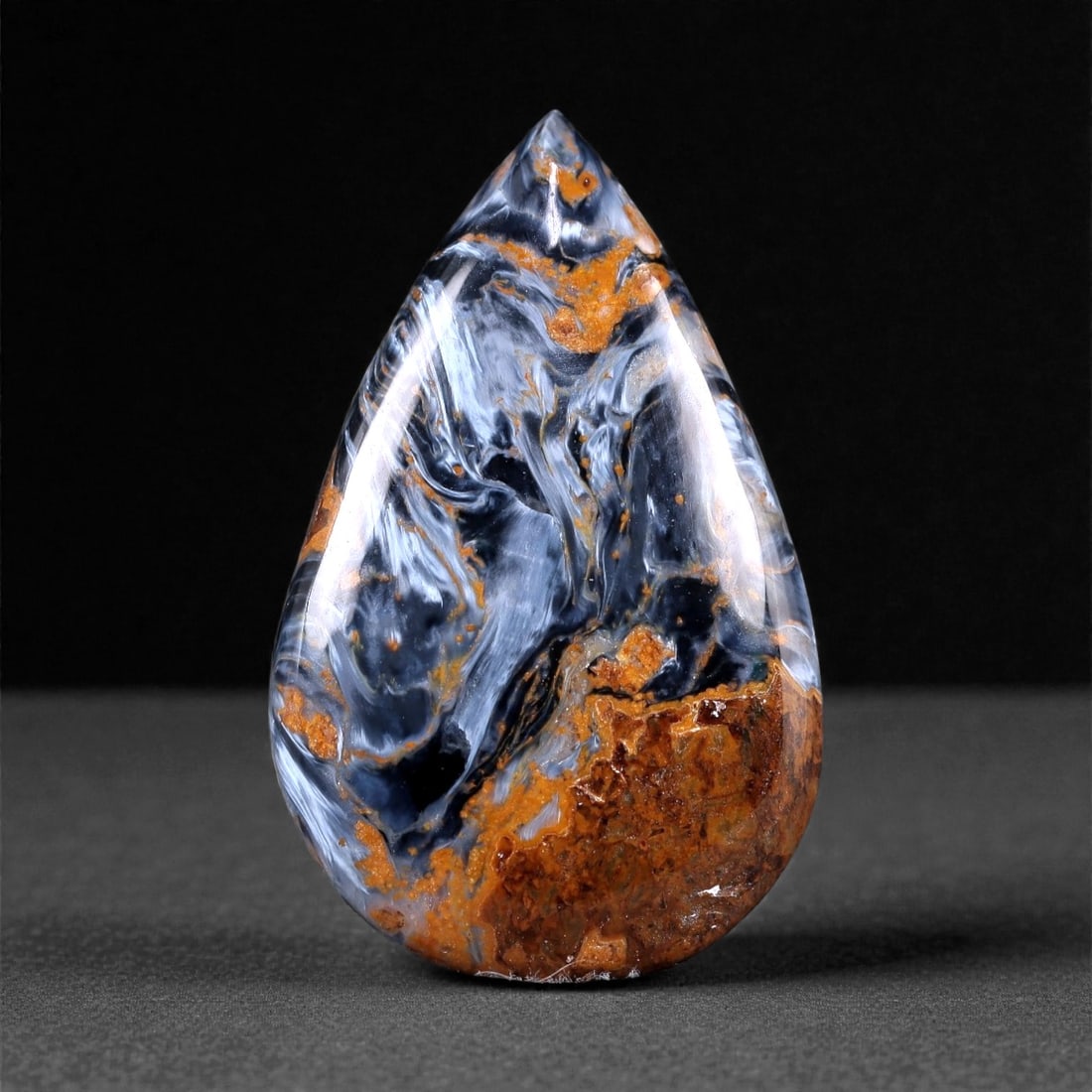 31.95 Carats Midnight Swirl Pietersite Cabochon - Natural African Gem, 41XC: This mesmerizing 33 x 20 mm pietersite cabochon showcases a dramatic interplay of deep midnight blues, smoky grays, and earthy rust tones, evoking a sense of motion and elemental energy. The surface g