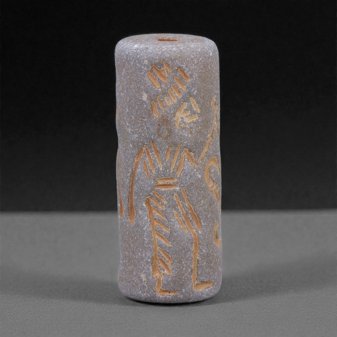 A Near Eastern Steatite Cylinder Seal, 3rd Millennium BCE, 96L: Carved from steatite with a fine-grained grey surface and areas of lighter abrasion, the seal is cylindrical in form and pierced longitudinally for suspension. The exterior is engraved in shallow line