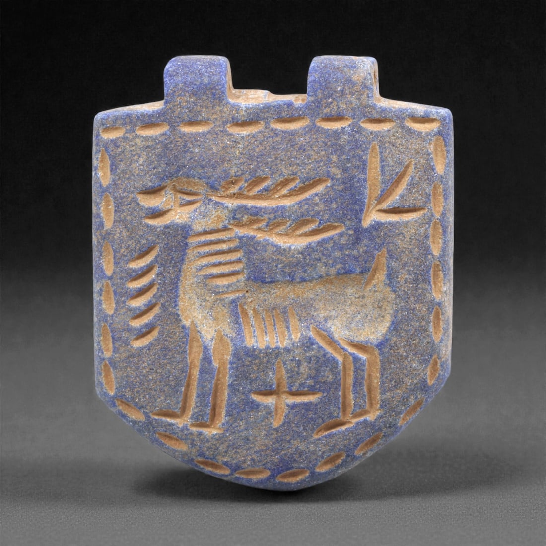 A Sasanian Lapis Lazuli Amulet, 3rd-7th Century CE, 4.1cm, 3Q: Carved from deep blue lapis lazuli with visible lighter inclusions and natural granular texture, the object is finished with a flat reverse and a front surface worked in low relief. The carving is exe