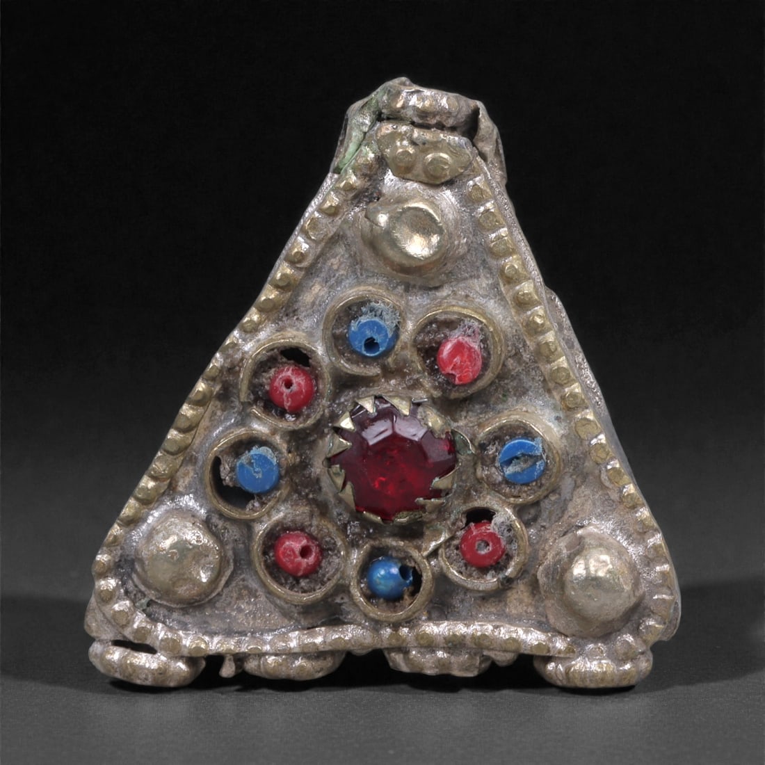 Silver Triangular Amulet - Himalayan Glass Inlay Pendant, 4.2cm, 47X: The amulet is constructed from silver sheet, formed into a compact hollow triangular pendant with applied repousse bosses and inset settings. The surface is framed by a dotted border, while the interi