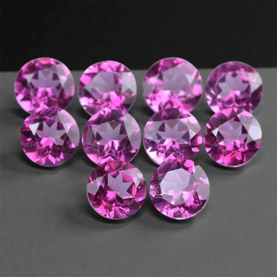 3.11 Carats Vivid Pink Topaz Round Parcel - Natural Brazilian Stones, 7XC: This eye-catching parcel features ten round-cut pink topaz stones totaling 3.11 carats, each measuring approximately 4 x 2.4 mm. The gems exhibit a vivid magenta-pink hue with excellent brilliance and