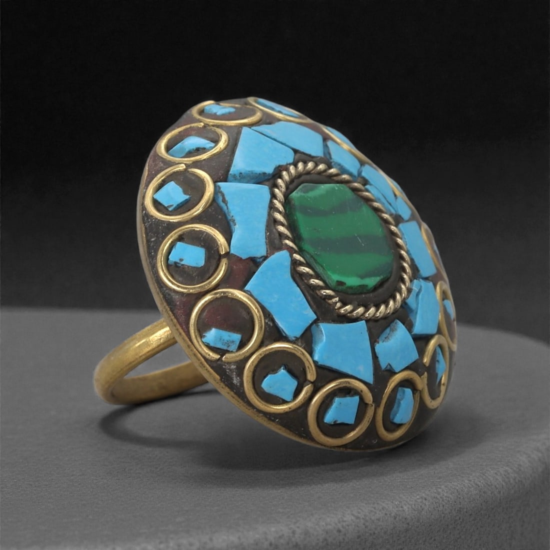 Himalayan Style Brass Ring - Turquoise Inlay Malachite Setting, 54XF: This ring is constructed with a broad circular bezel formed in brass, its surface arranged around a central oval malachite cabochon framed by a twisted rope border. Radiating outward is a mosaic of tu