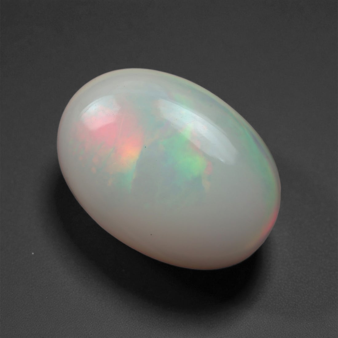 4.63 Carats Misty Aurora Opal Cabochon - Natural Ethiopian Welo Stone, 88XB: This soft white Ethiopian opal reveals delicate flashes of pink, mint green, and golden yellow beneath its silky, translucent surface. With its smooth oval shape (16.1 x 11.9 mm), the cabochon evokes
