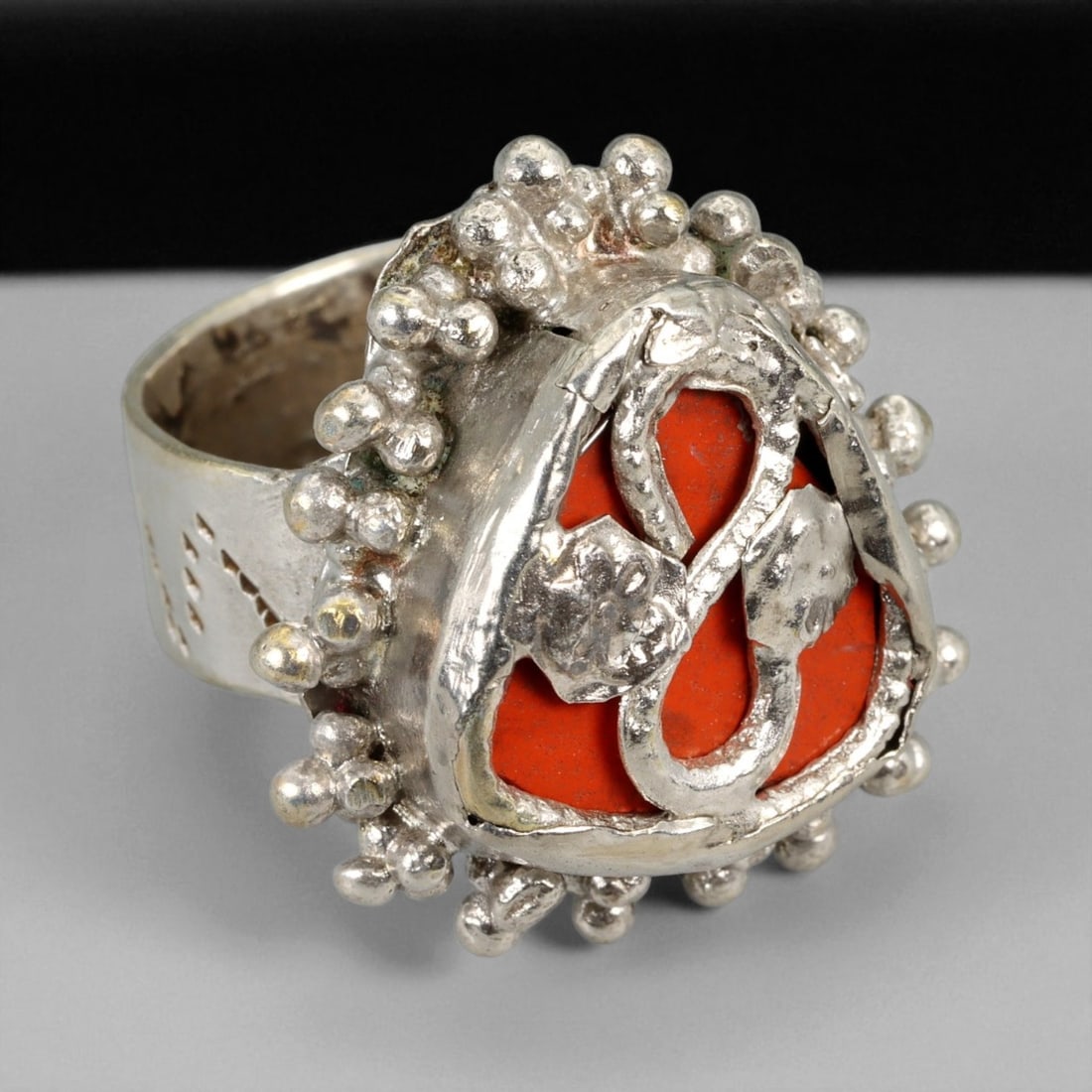 A Central Asian Silver Ring with Coral Inlay and Granulated Design, c. 19th-20th Century, US 9, 28XD: This striking A silver ring embodies the distinctive craftsmanship and spiritual expression of Central Asian tribal silversmiths from the late 19th to early 20th century. The bold triangular bezel, ad