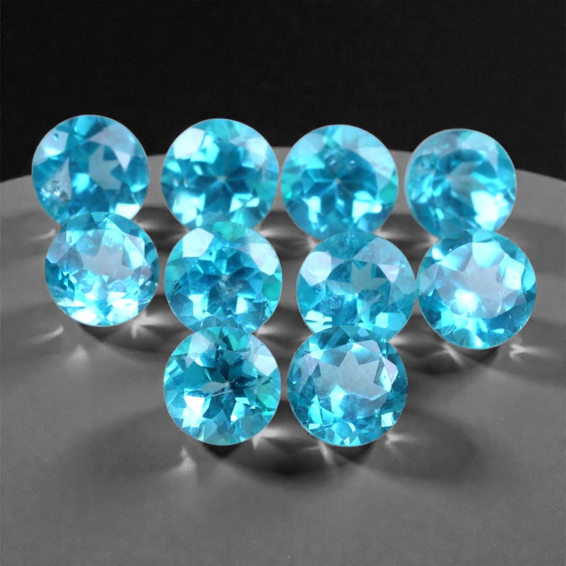 3.09 Carats Paraiba Blue Topaz Round Parcel - Natural Brazilian Stones, 61XB: This vibrant parcel of Paraiba blue topaz stones offers a total weight of 3.09 carats across ten calibrated round cuts, each measuring approximately 4 x 2.4 mm. The gems dazzle with an intense neon-aq