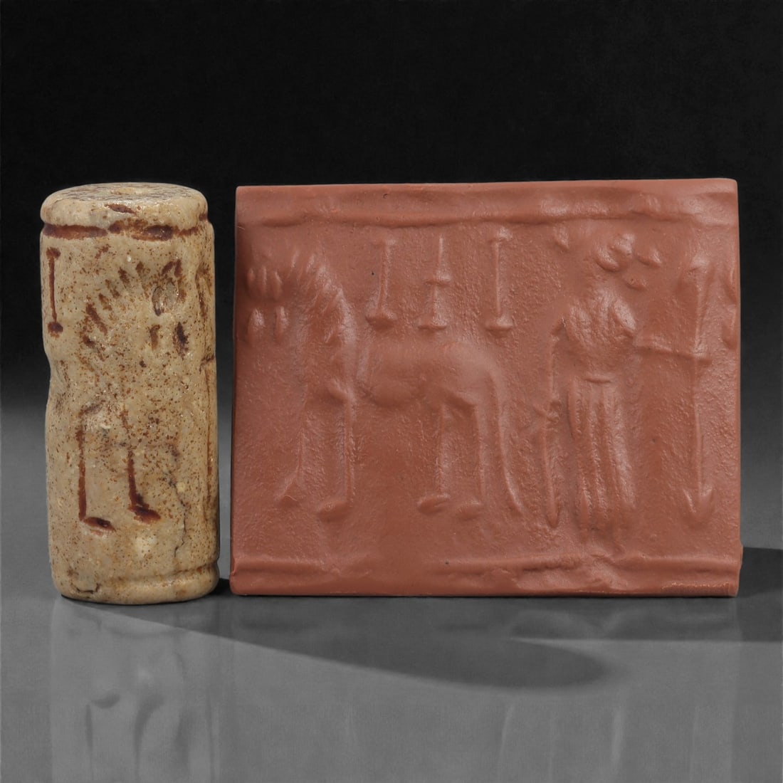 A Near Eastern Stone Cylinder Seal, 3rd Millennium BCE, 3.9cm, 95LM: Carved from stone with darker surface mottling, the cylindrical seal bears a continuous engraved scene. The carving is executed in shallow linear grooves typical of Early Bronze Age glyptic traditions