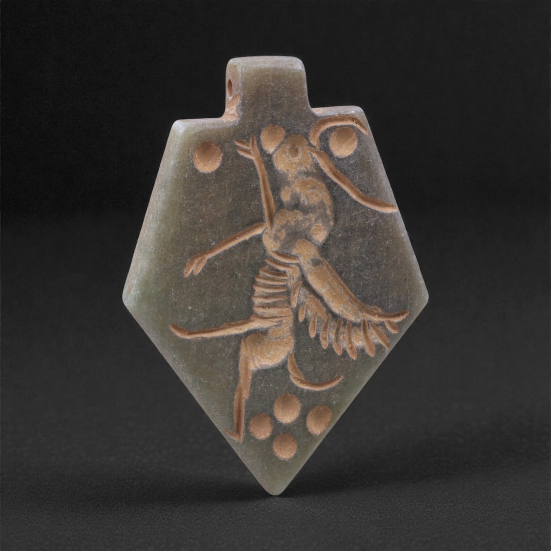 An Eastern Iranian Serpentine Amulet, Islamic Period, 9th-10th Century CE, 4.6cm, 59K: Carved from pale green serpentine with a smooth, slightly translucent surface, the object is worked in low relief on one face, with the reverse left plain and undecorated. The carved elements are defi