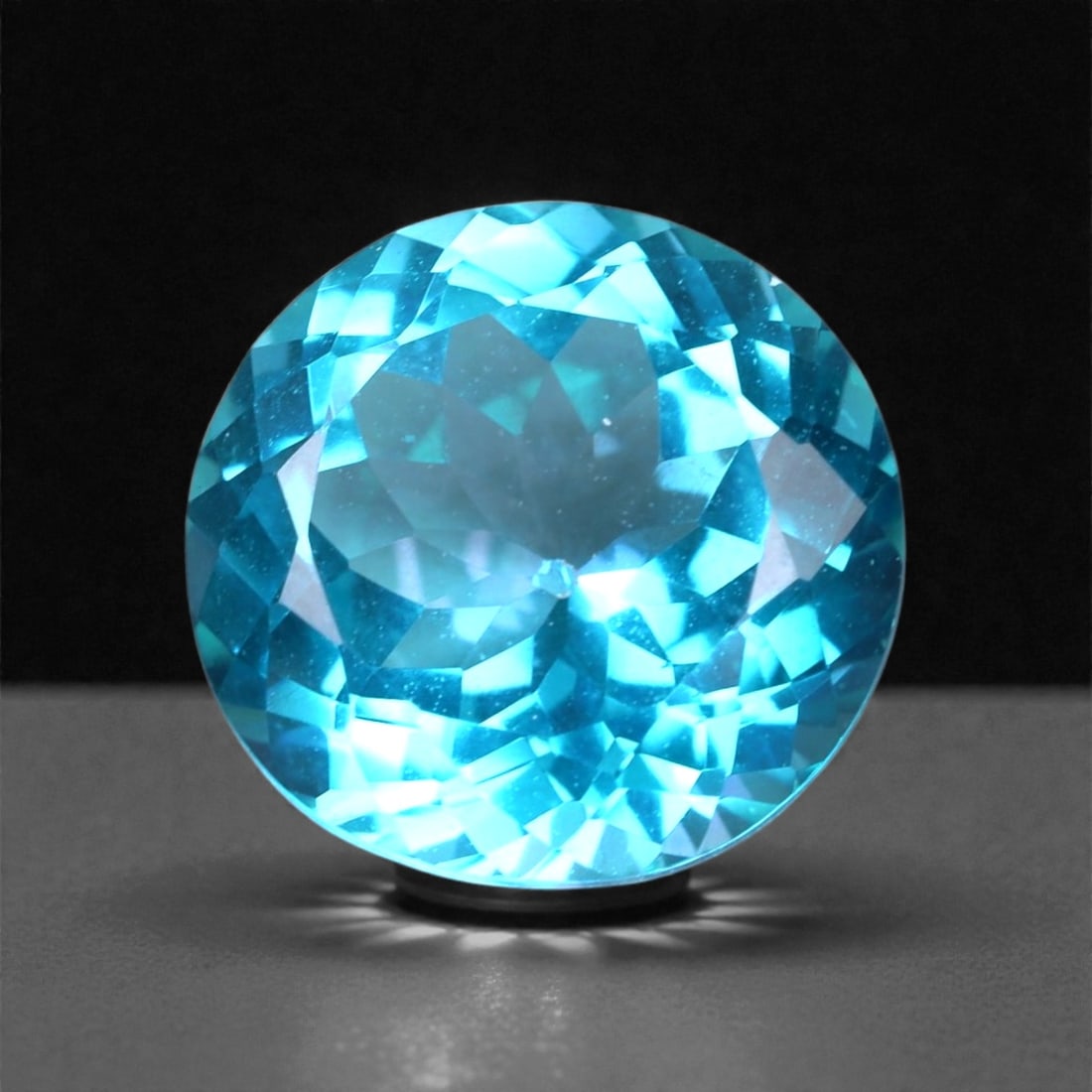 4.01 Carats Paraiba Blue Topaz Round - Natural Brazilian Gem, 67XB: This luminous 4.01 carat Paraiba blue topaz radiates with neon brilliance and crystalline clarity, cut into a perfectly symmetrical round that amplifies its electric aqua tone. Measuring 9.9 x 5.7 mm,
