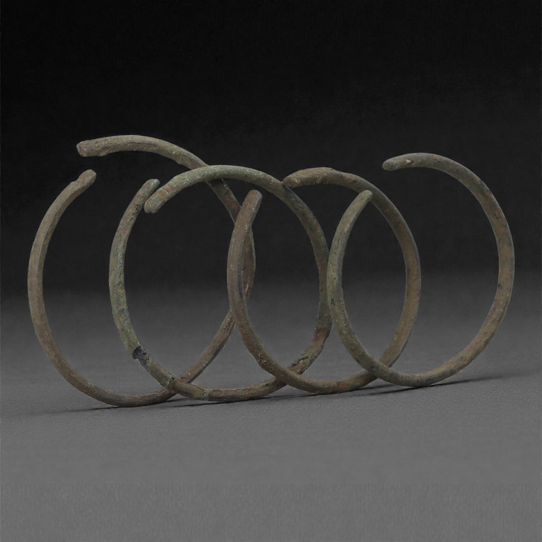 A Group of Roman Bronze Bracelets, 1st-3rd Century CE, 43H: Cast in bronze and formed as slender open circular bands, the bracelets exhibit narrow rounded profiles with slight irregularities characteristic of ancient manufacture and subsequent burial alteratio