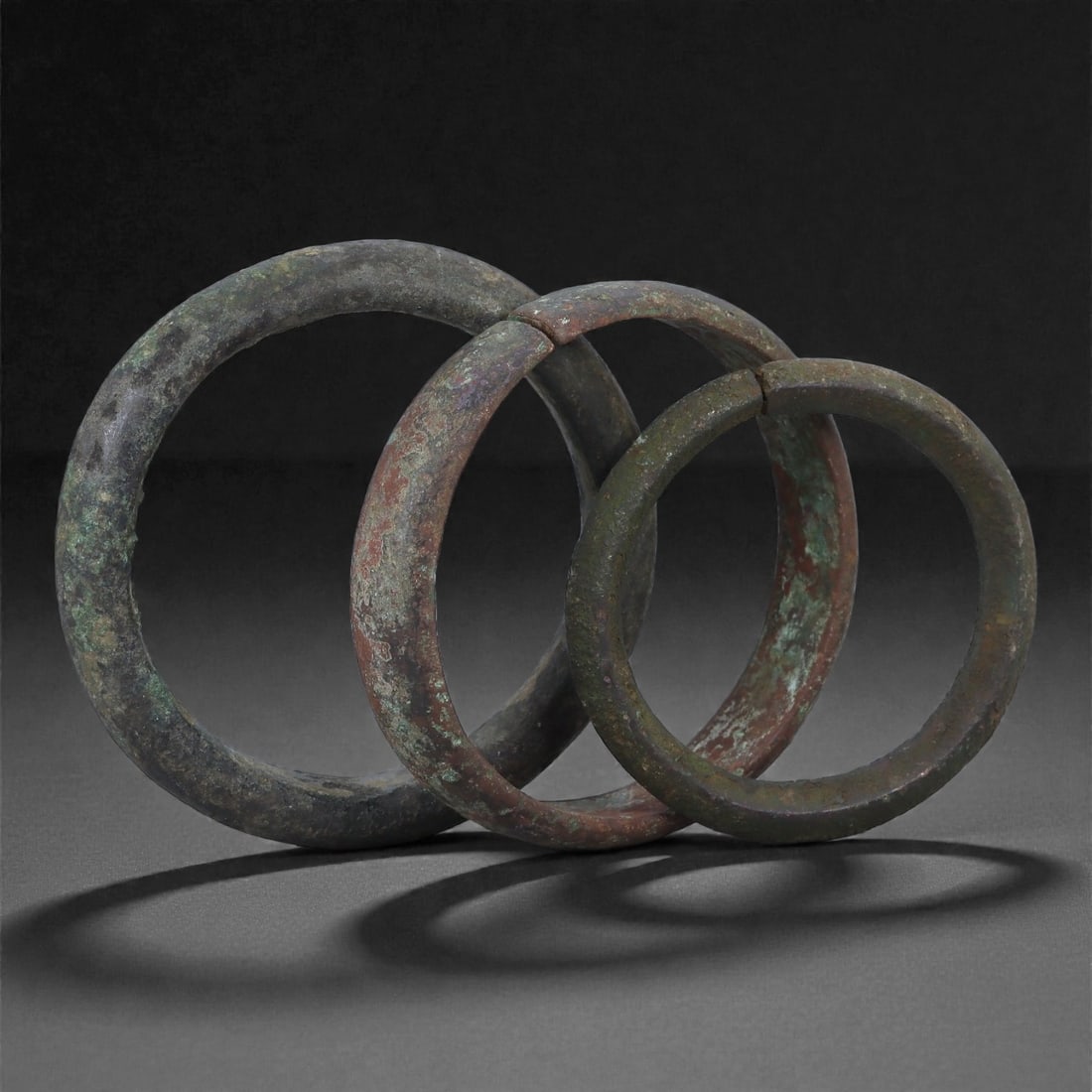 A Group of Roman Bronze Bracelets, 1st-3rd Century CE, 90H: Cast in bronze and formed as open circular bands, the bracelets exhibit thick rounded profiles with slight irregularities resulting from ancient manufacture and later burial distortion. The surfaces r