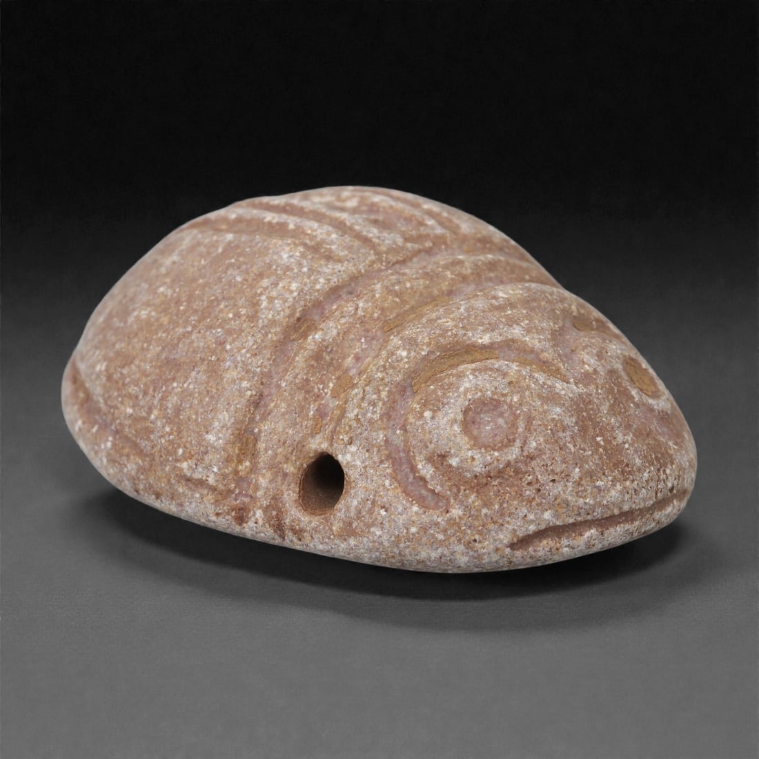 A Sino-Mongolian Stone Zoomorphic Amulet, 2nd-1st Millennium BCE, 70LR: Carved from a pinkish-brown stone with a granular surface, the object is shaped as a compact, domed zoomorphic form with a broad rounded back and a slightly projecting snout. The eyes are rendered as