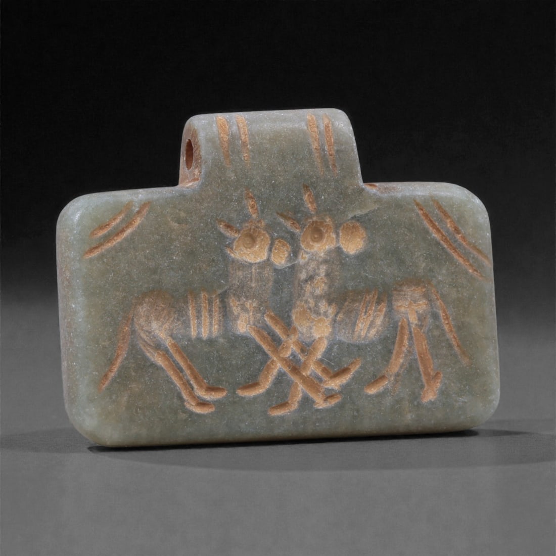 An Eastern Iranian Serpentine Amulet, Islamic Period, 9th-10th Century CE, 3.5cm, 7K: Carved from pale green serpentine with a smooth, slightly translucent surface, the object is worked in low relief on one face, with the reverse left plain and undecorated. The carved elements are defi