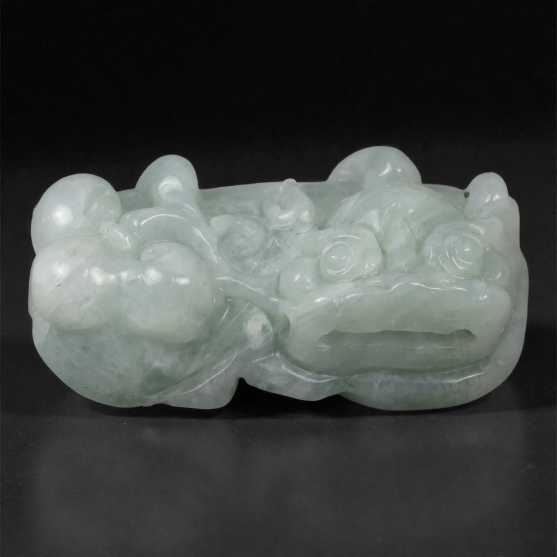 Chinese Jade Pi Xiu - Oriental Guardian Amulet, 77G: Carved from pale green translucent jade with a softly polished surface, this small sculptural amulet depicts a reclining pi xiu rendered in compact relief. The mythical creature is modeled with a roun
