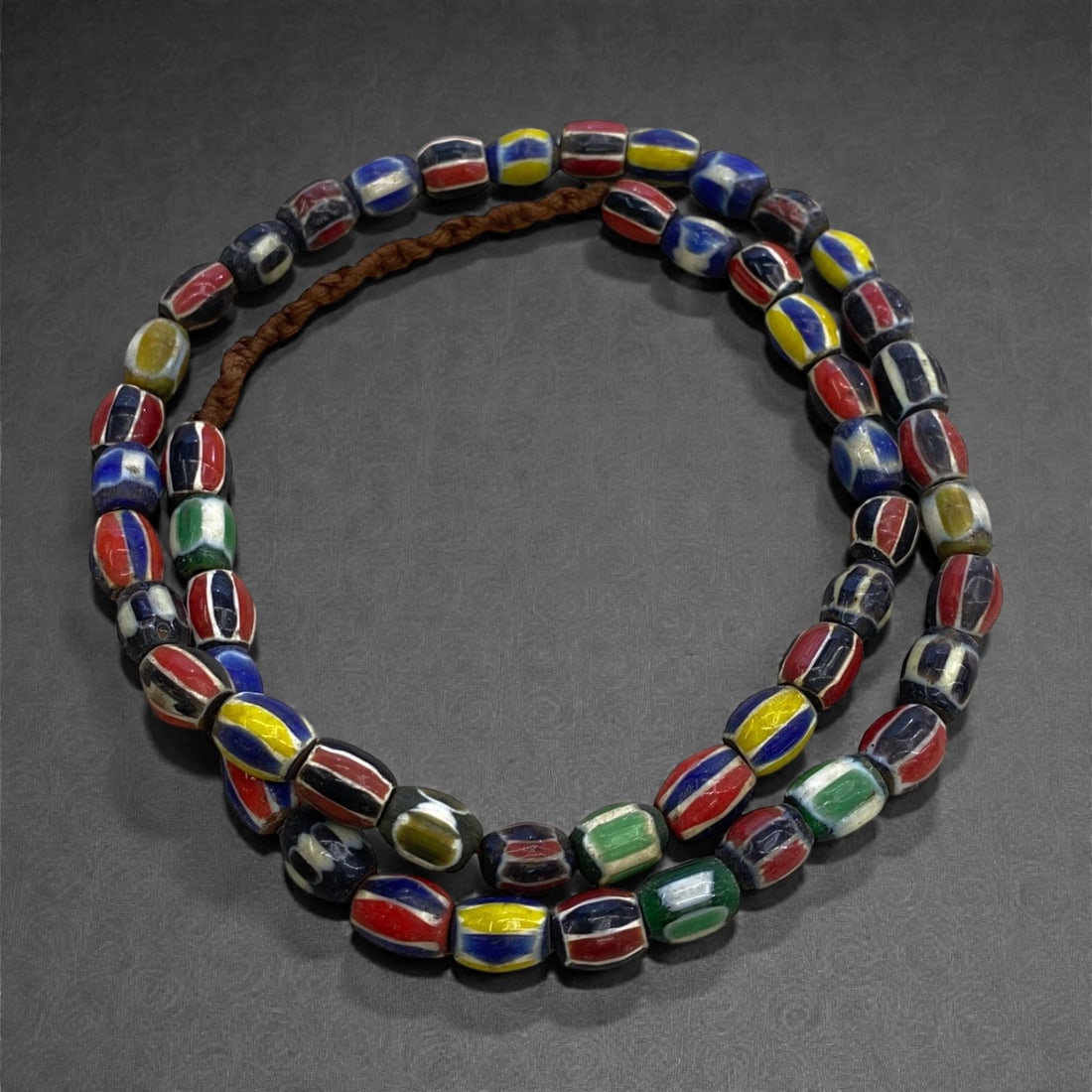 A Venetian Glass Trade Bead Strand, Late 19th-Early 20th Century, 74g, 44AA: Composed of hand-drawn and hand-finished glass beads strung as a continuous strand, the assemblage consists predominantly of small spherical beads decorated with longitudinal marvered striping in poly