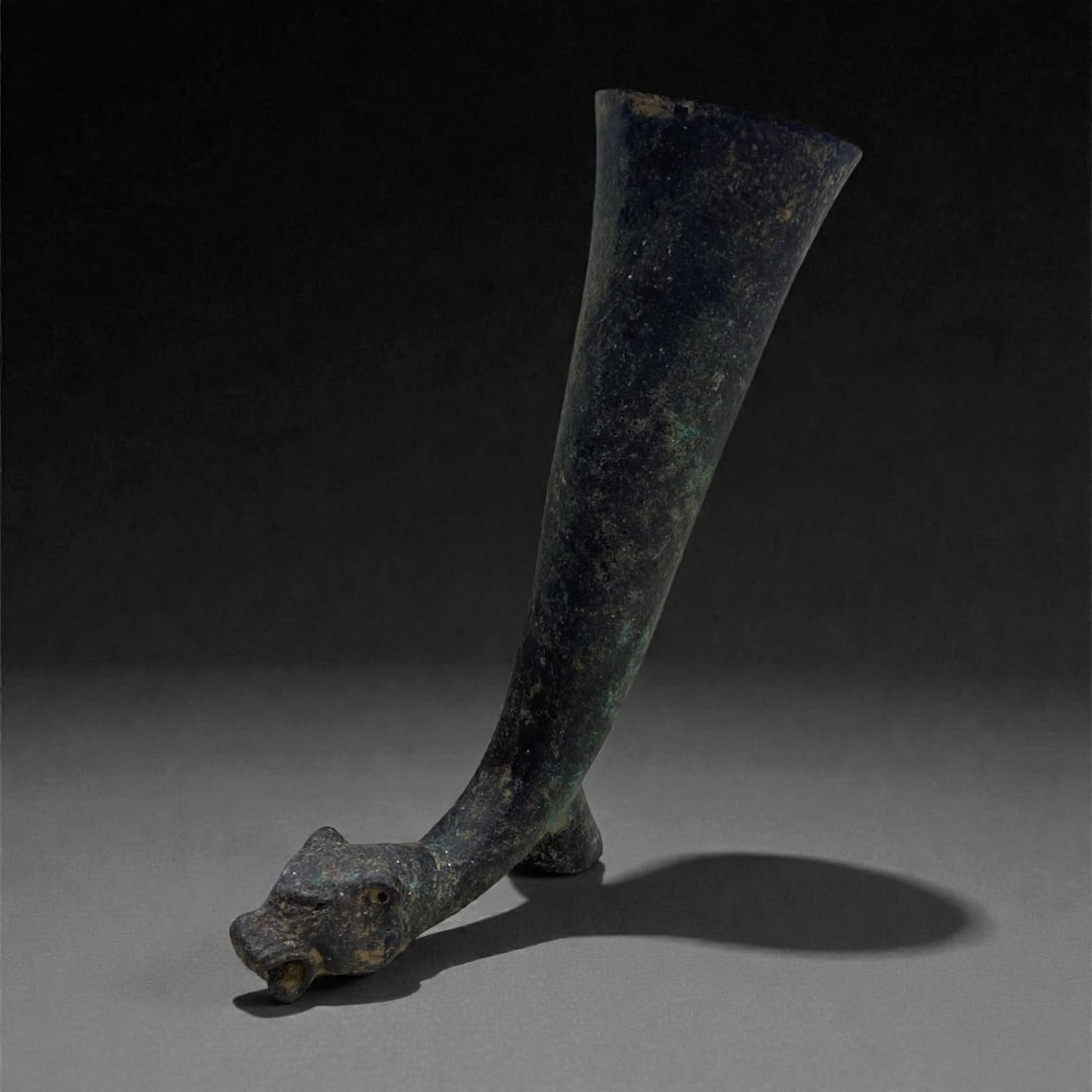 A Near Eastern Bronze Rhyton with Lioness Protome, 1st Millennium BCE, 160g, 33BB: Cast in bronze with a dark surface and extensive green and black patination, the rhyton is formed as a tapering, gently curved horn terminating in a modeled lioness head. The upper rim is flaring and