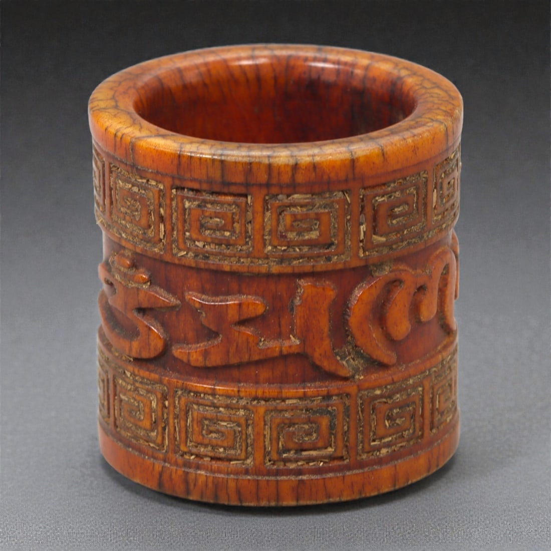 A Tibetan Bone Archer's Thumb Ring, 20th Century, 31FD: Carved from bone with a warm amber-brown patina and visible longitudinal grain, the ring is formed as a thick cylindrical band with a straight outer wall and a smoothly hollowed interior. The exterior