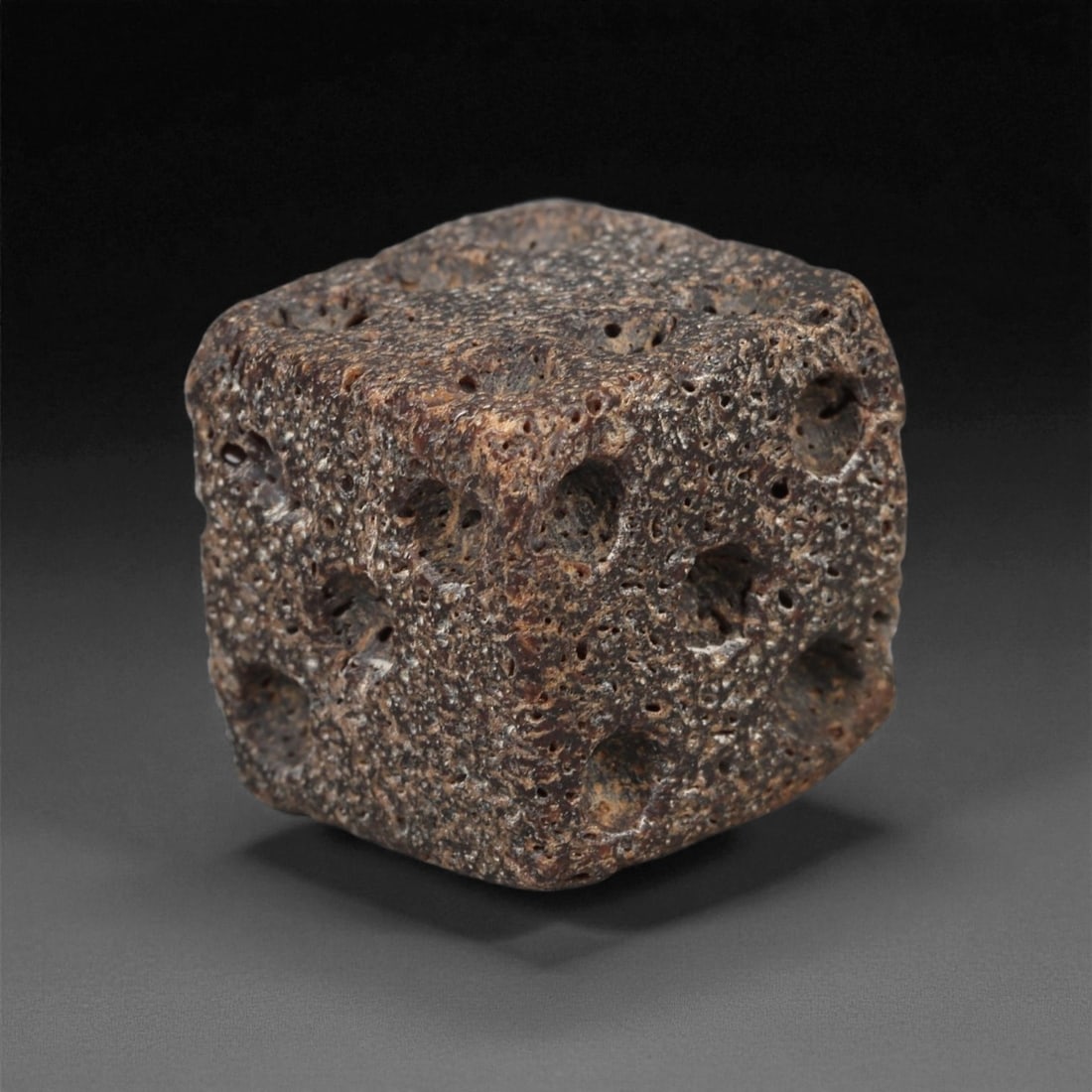 A Roman Bone Gaming Die, 1st-3rd Century CE, 1.4cm, 17ZB: Carved from dense bone, the object is shaped as a small cube with slightly rounded edges. Each face bears a series of drilled circular pips arranged in standard numerical configurations. The surfaces 