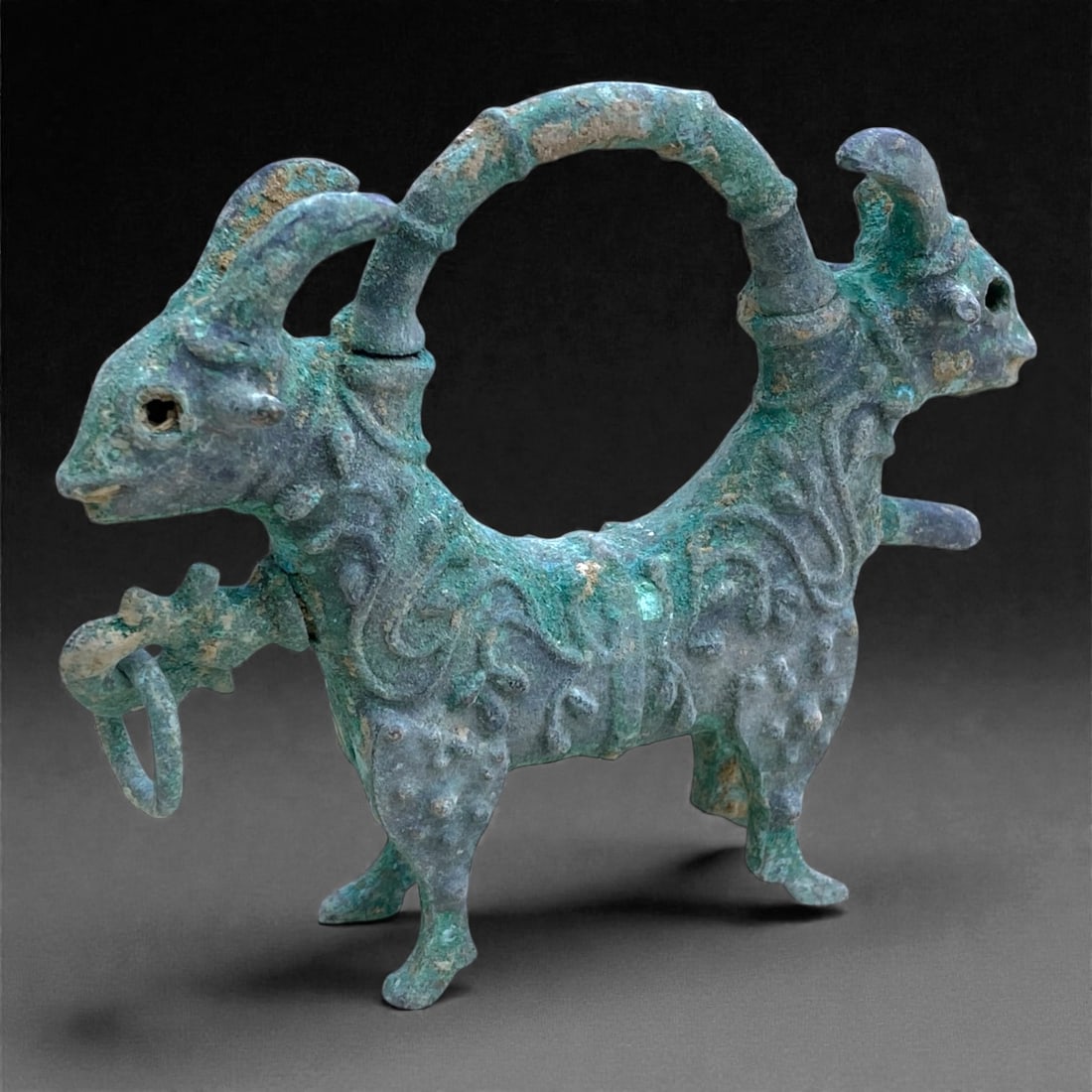 A Byzantine Bronze Zoomorphic Lock, 10th-11th Century, 184 g, 1AA: Cast in bronze and formed as a composite zoomorphic device, the lock is conceived as a standing quadruped with two opposed animal heads, likely caprids, projecting at either end. The bodies are joined