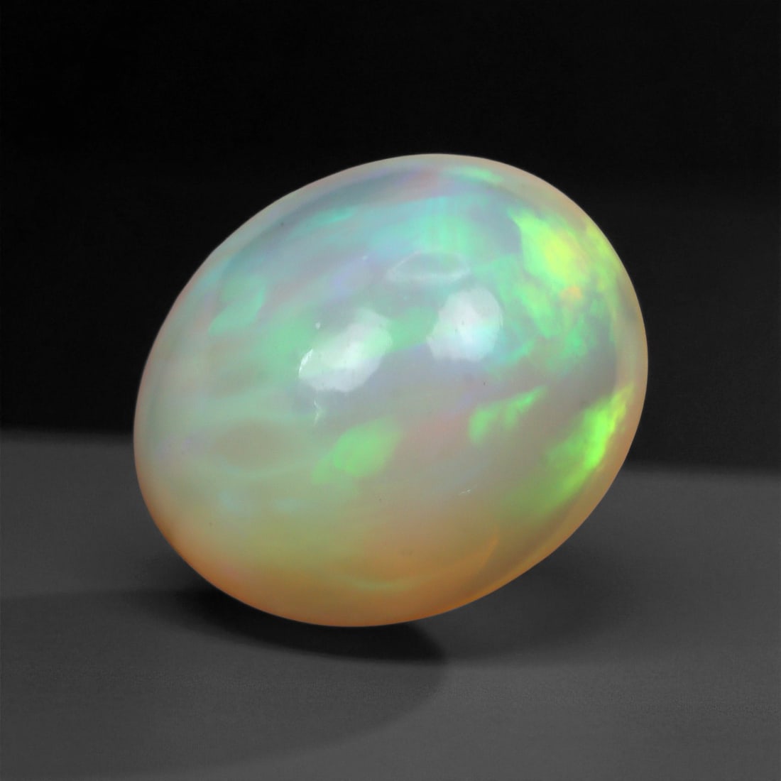 3.31 Carats Pastel Neon Welo Opal Cabochon - Natural Ethiopian Gemstone, 64XE: This glowing Welo opal shimmers with delicate flashes of mint green, lavender, sky blue, and soft amber beneath a translucent, honey-toned body. Its internal light play is gentle yet vivid, with broad