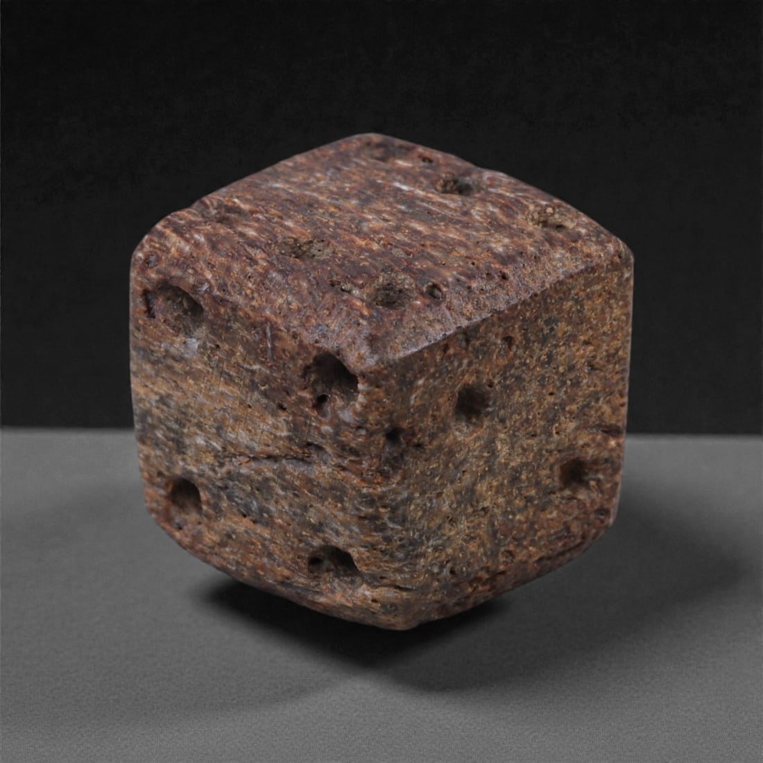 Ancient Roman Bone Gaming Die - Carved Dice, 1cm, 83E: Carved from dense animal bone, this miniature gaming die is carefully shaped into a cubic form with evenly proportioned faces and rounded edges softened through long use. The pips are drilled as shall