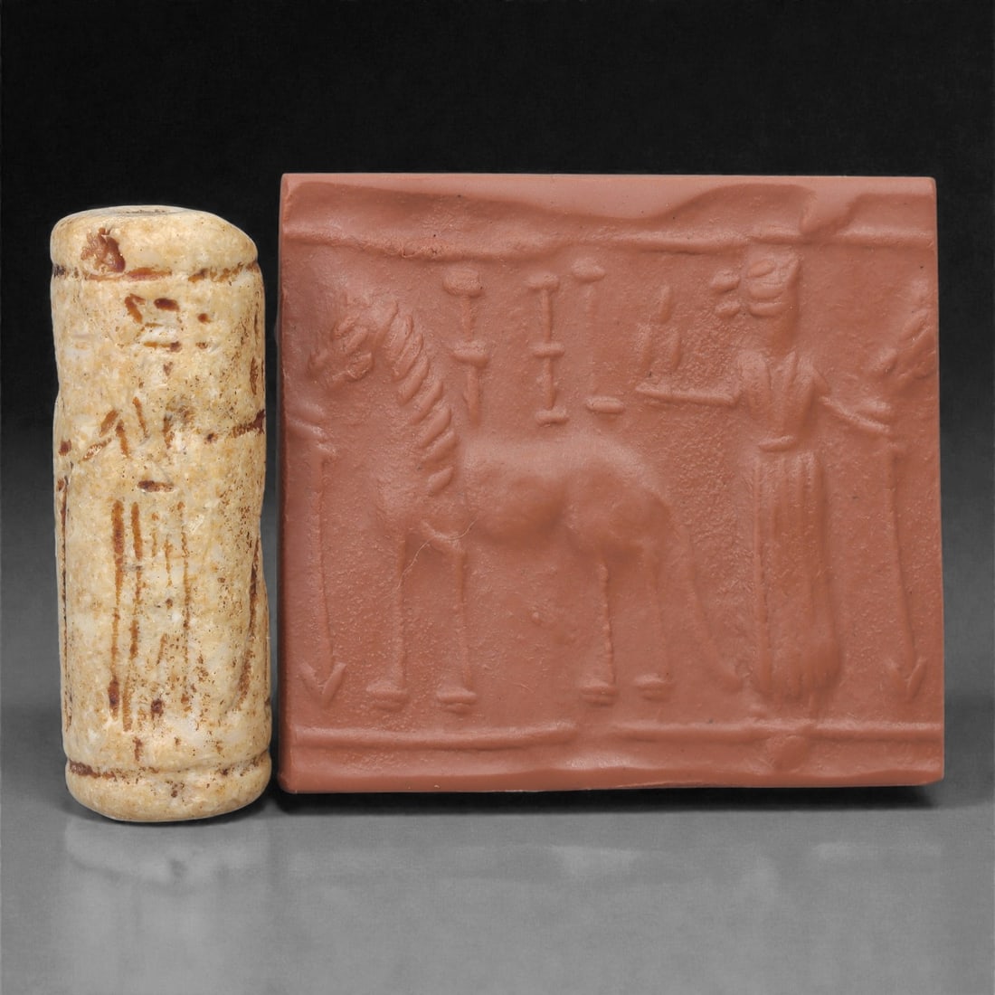 A Near Eastern Stone Cylinder Seal, 3rd Millennium BCE, 4.5cm, 47LJ: Carved from stone with darker surface mottling, the cylindrical seal bears a continuous engraved scene. The carving is executed in shallow linear grooves typical of Early Bronze Age glyptic traditions