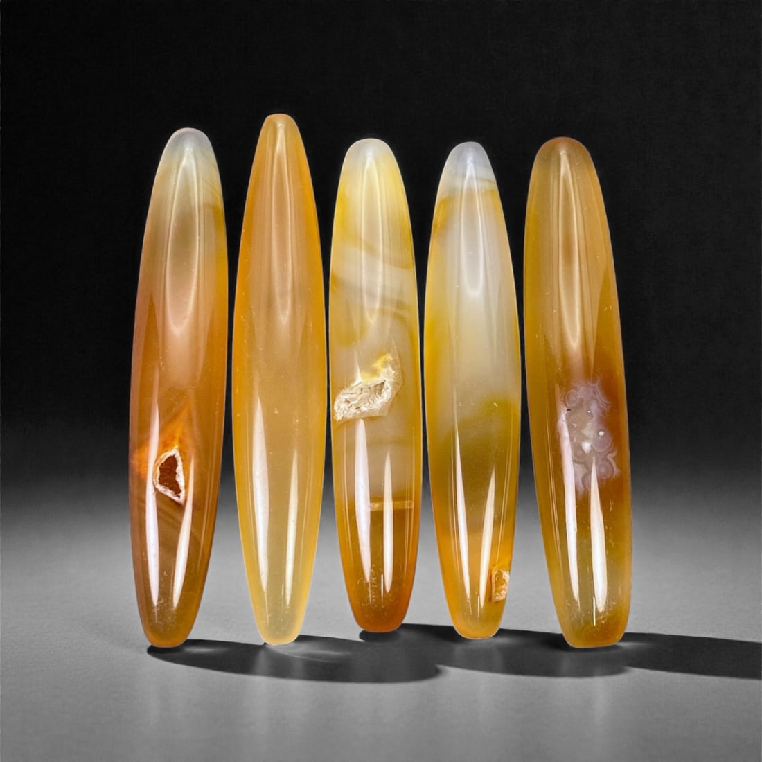 Tibetan Carnelian Ritual Beads, 19th-20th Century CE, 4.8-5.1cm, 2L: Carved from translucent orange carnelian with natural internal banding, the group comprises elongated, double-conical elements with smoothly polished surfaces. Each bead is unperforated, indicating a 