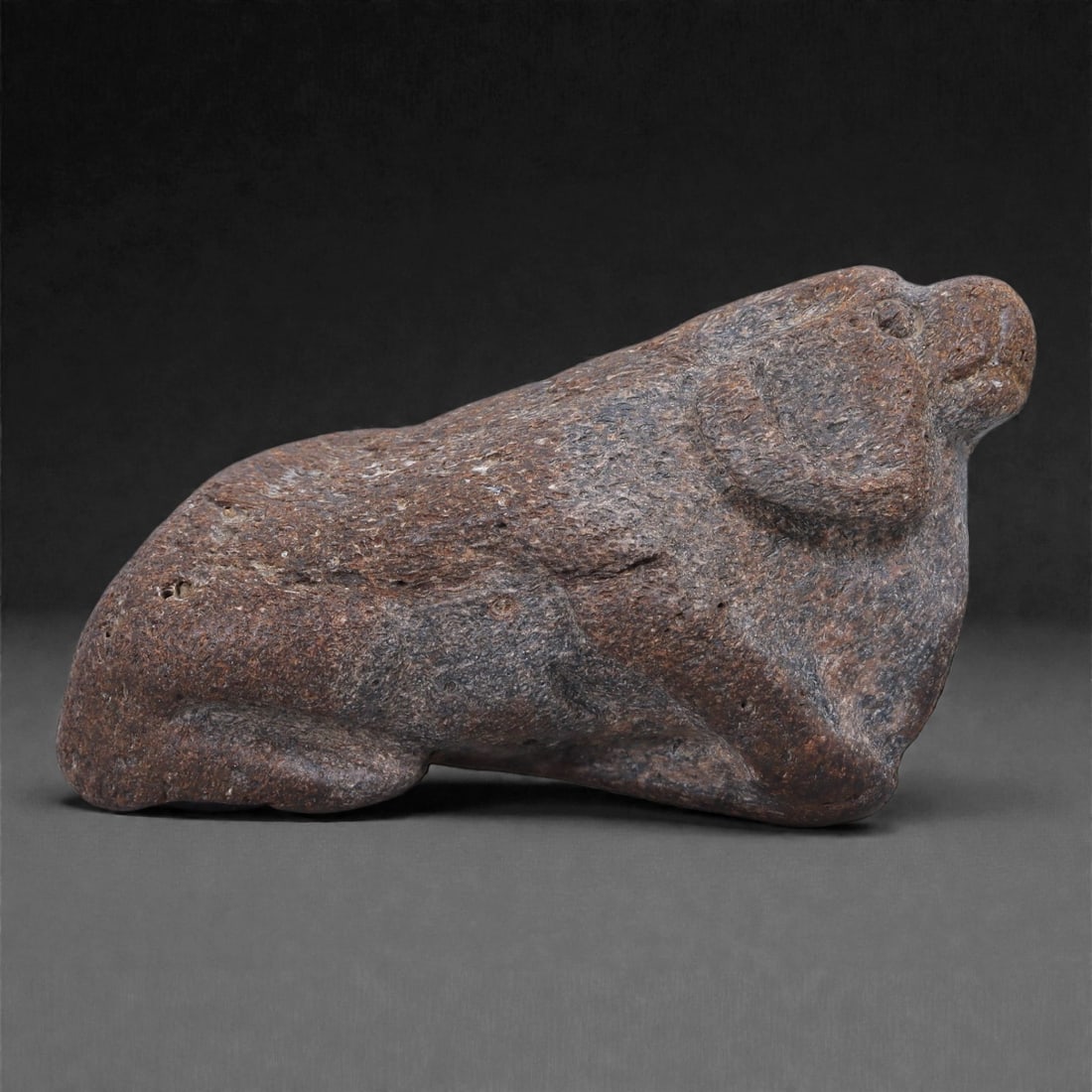Ancient Stone Bovid - Near Eastern Animal Figurine, 16F: Carved from dense, heavy stone, this compact zoomorphic bovid figure presents a mineralized surface with a pronounced bone-like appearance, closely resembling fossilized osseous material. The stone di