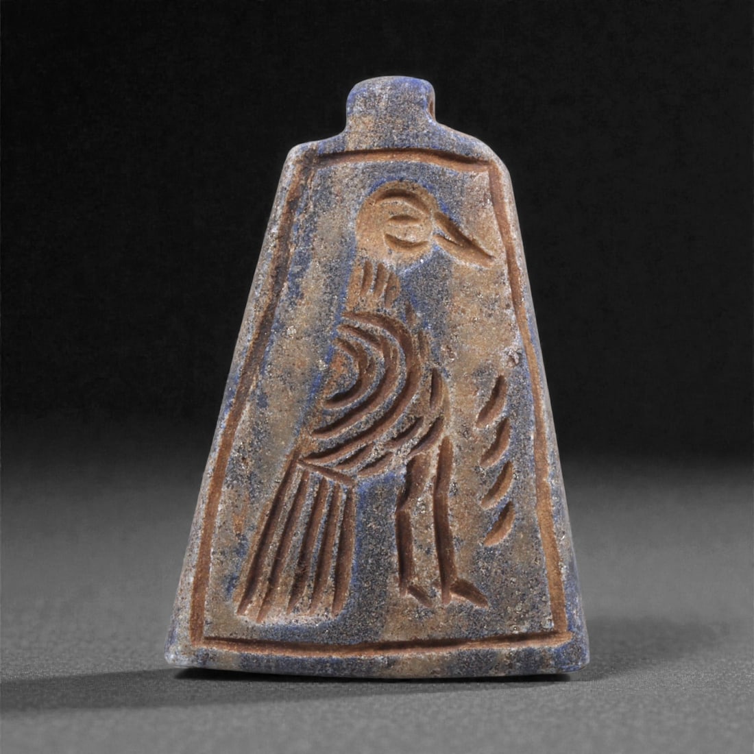 A Sasanian Lapis Lazuli Amulet, 3rd-7th Century CE, 4.3cm, 20Q: Carved from deep blue lapis lazuli with visible lighter inclusions and natural granular texture, the object is finished with a flat reverse and a front surface worked in low relief. The carving is exe