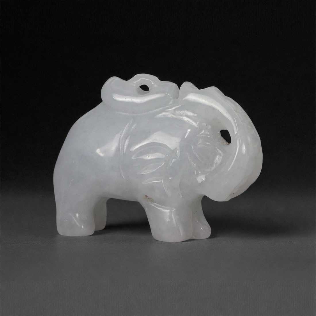 Chinese Jade Elephant Pendant - Oriental Animal Amulet, 74G: Carved from pale, translucent jade with a smooth polished surface, this miniature pendant depicts a stylized elephant rendered in compact sculptural form. The animal is shown in profile with simplifie